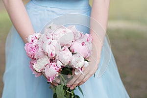 Bridesmaid in blue dress hold bouquet with white and pink peony