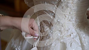 Bridesmaid helping for young bride to put on her wedding dress. Luxury bridal gown