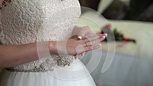 Bridesmaid helping for young bride to put on her wedding dress. Luxury bridal gown