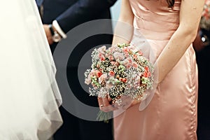 Bridesmaid holding pink bouquet with roses in church at wedding