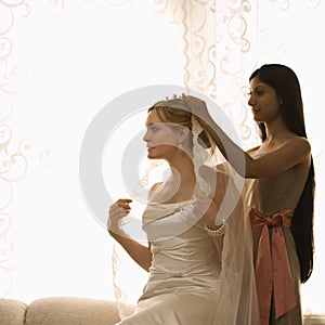 Bridesmaid placing veil.