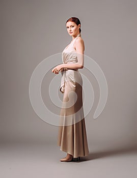 Bridesmaid`s dresses. Elegant moscato dress. Beautiful ivory silk evening gown. Studio portrait of young happy ginger woman. Tran