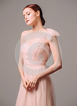 Bridesmaid`s dresses. Elegant moscato dress. Beautiful pink chiffon evening gown. Studio portrait of young happy ginger woman. Tr