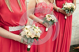 Bridesmaid the same dressed with bouquets of roses and other flo