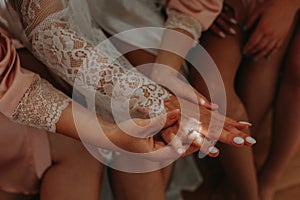 The bridesmaids admire the wedding ring on the bride's finger. The bride and her fun friends are celebrating a bachelorette party