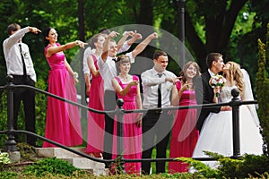 Bridesmaids and groomsmen stare at a kissing wedding couple