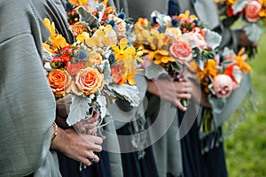 Bridesmaids holding their wedding bouquets of flowers with yellow, red, blue and orange flowers