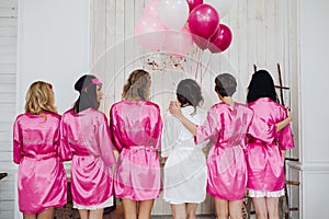 Bridesmaids in pink silk robes with the word `bridesmaid` on bac photo