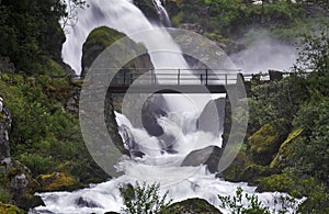 Bridge across the stream near a powerful waterfall
