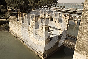 Bridge across water moat at the Scaliger Castle entrance to old town, Sirmione, Lombardy, Italy. Aged photo effect