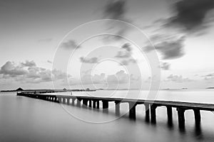 Bridge on beach in sunrise and sea wave