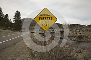 Bridge freezes before road sign next to river