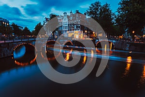 Bridge illumination and boat light trails in evening Amsterdam with reflection in Herengracht canal. Typical dutch