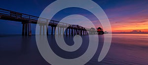 Bridge leading to typical houses in Naples Pier Florida at sunset