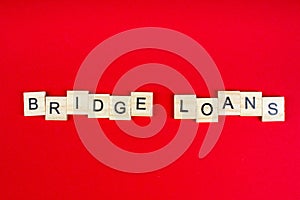 Bridge loans- word composed fromwooden blocks letters on red background, copy space for ad text photo