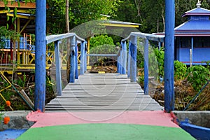 A bridge made of wood painted blue crosses a small river.