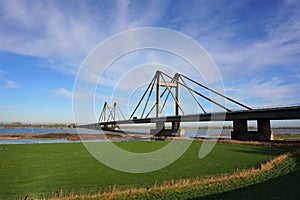 Bridge with motorway the Willem Alexander bridge over the river Maas built on pillars and connecting land.