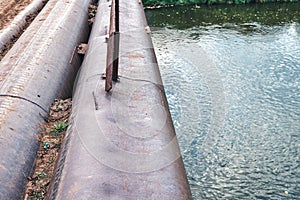 Bridge of old metal pipes over tranquil river at rural site