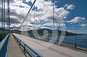 a bridge over the a channel over background with hills and clouds in a sunny day