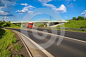 Bridge over an empty highway in the countryside, under a bridge passing two trucks