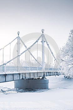 Bridge over frozen river and trees in hoarfrost. Fine art