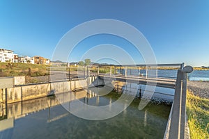 Bridge over lake with lakefront buildings and mountain view under blue sky