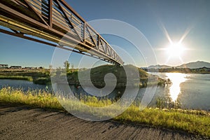 Bridge over a lake and road viewed against sun and blue sky on a sunny day