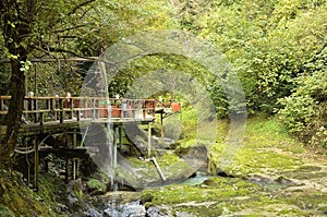 Bridge over a mountain river with an artificial waterfall