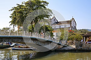 View to bridge over river Pereque-Acu with trees and an old church in the background, in historic town Paraty, Brazil