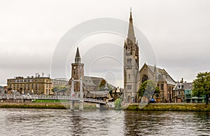 Bridge over river Ness leading to the famous tall Gothic style Free Church of Scotland, Inverness