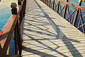 Bridge over the river in a park concrete floor wooden rail blue sky reflects down the river