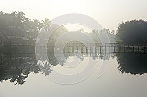 Bridge over river. Tropical landscape. Morning fog. Beautiful scenery with a bridge over the river. The lights of a sun