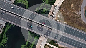 Bridge over a small river with cars driving on it view from the top, the river is overgrown with green grass