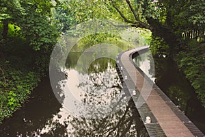 Bridge in the park faded. Walkway over water in forest filtered. Curve path over pond in summer park. Peaceful place.