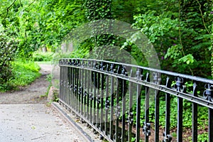 Bridge in the park. Forged hand-made rods. Alley in the park with the perspective of the bridge