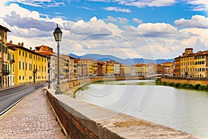 A bridge passes over the river and houses on both sides are overlooking the water. Pisa, Arno river, Ponte di Mezzo bridge and photo