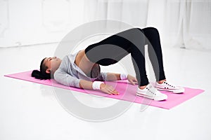 Bridge pose sporty woman doing warming up exercise for spine, backbend, arching stretching her back working out at home