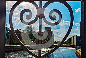 A bridge railing in the shape of a heart in the government district of Berlin with a view to the Spree and the Reichstag