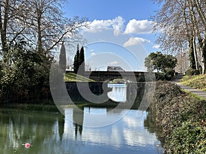 A bridge with a reflection in the water of Canal du Midi in Ponts Jumeaux, Toulouse, Occitania, France, February 2023