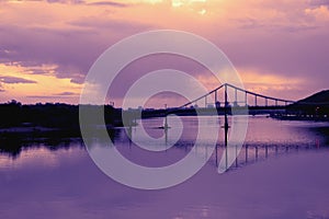 Bridge reflection in water surface of river Dnieper duaring sunset time.