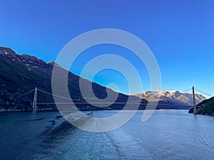 Bridge spanning a river, surrounded by majestic snow-capped mountains in the background