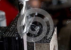 Bridgeport CNC end mill finishing a stack of steel plate with metal filings chips and light smoke