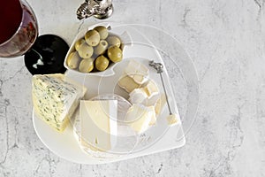 brie, camembert, gorganzola with olives and cherry tomatoes. Soft cheese with white and blue mold, olives and olive oil