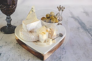 brie, camembert, gorganzola with olives and cherry tomatoes. Soft cheese with white and blue mold, olives and olive oil