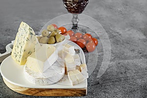 brie, camembert, gorganzola with olives and cherry tomatoes. Soft cheese with white and blue mold, olives and olive oil