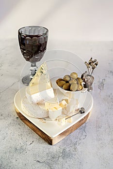 brie, camembert, gorganzola with olives and cherry tomatoes. Soft cheese with white and blue mold, olives and olive oil