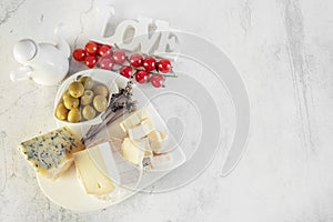 brie, camembert with olives and cherry tomatoes. Soft cheese with white mold, olives and olive oil. Inscription love.