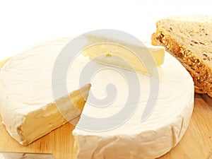 Brie cheese on wooden desk with knife isolated