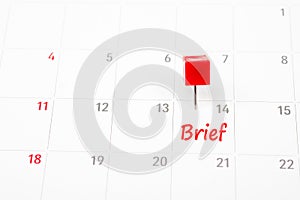 Brief written on  a calendar with a red push pin to remind you and important appointment