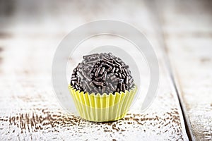 Brigadeiro or negrinho, a Brazilian chocolate candy common at children`s parties, on wooden table on white background photo